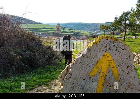 Man with big backpack walks on the french Way of `Camino de Santiago` in Winter. Pilgrimages on their journey through Spain. Stock Photo